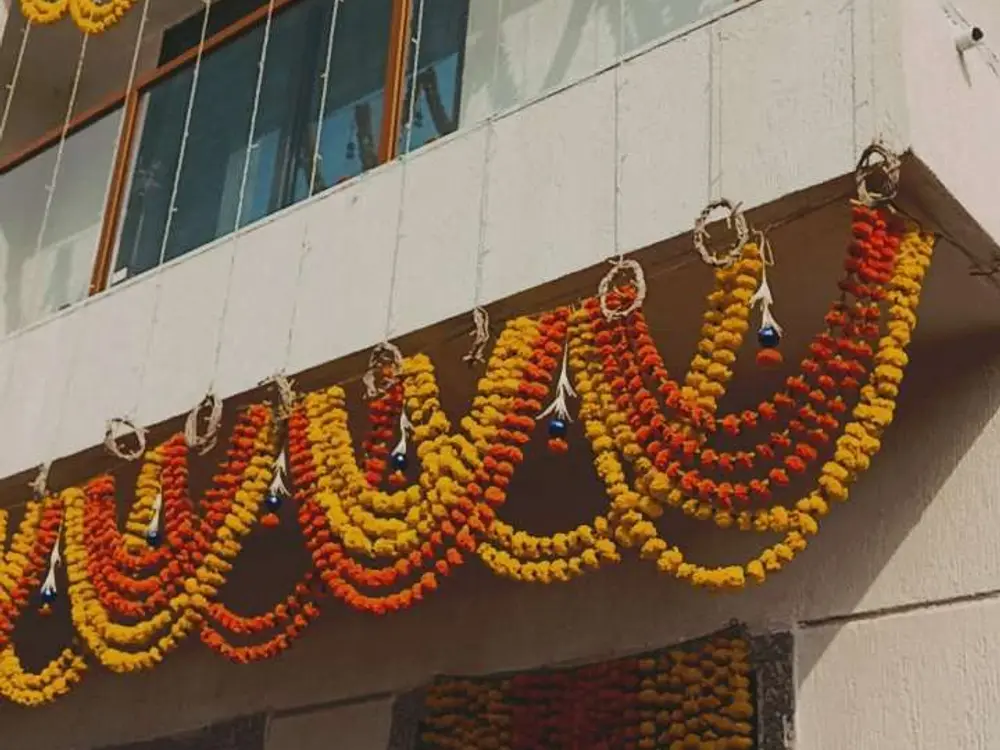 Orange and yellow marigold swags hanging in rows along the balcony of a white house front
