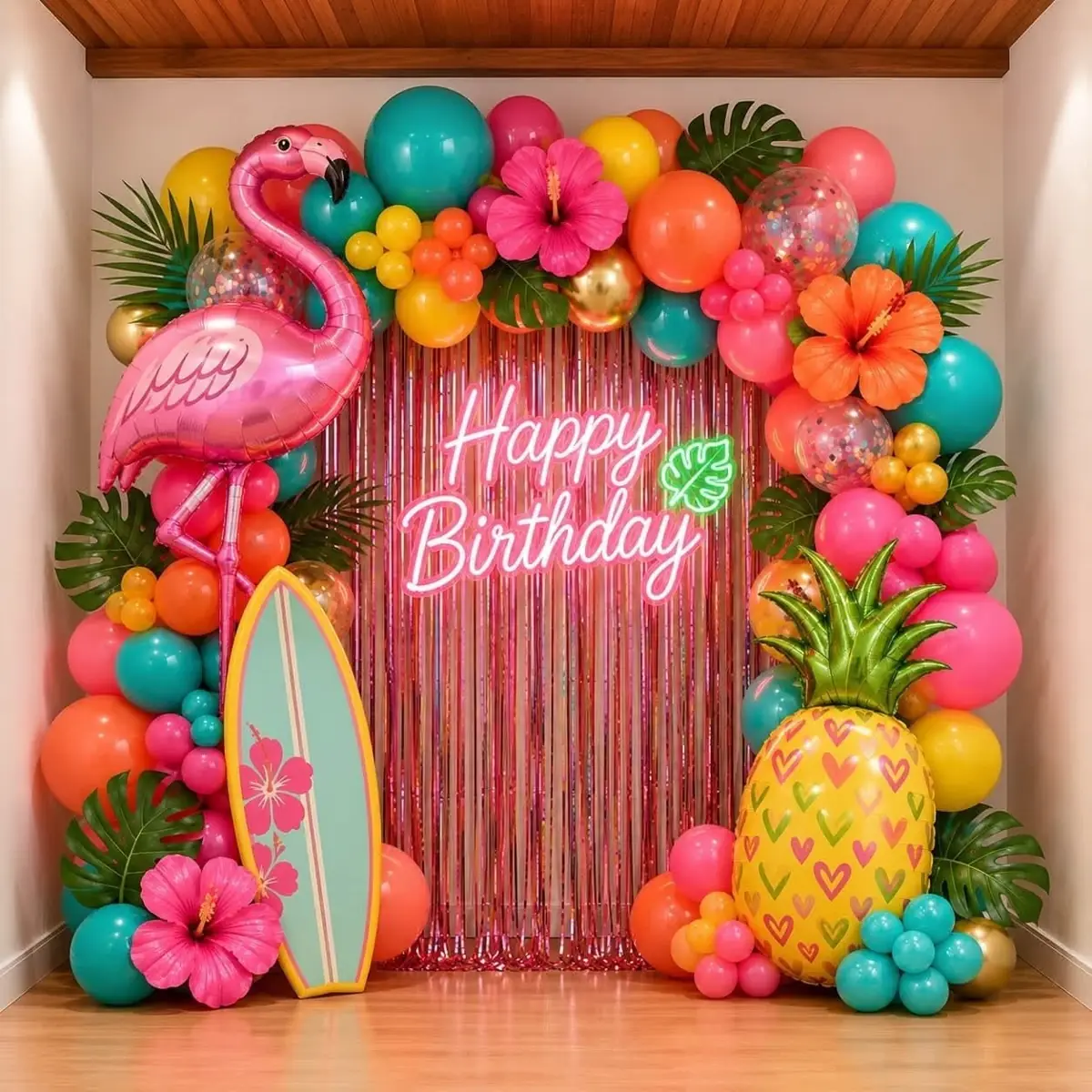 Tropical birthday arch with a flamingo foil, a pineapple foil, hibiscus flowers and a pink fringe curtain