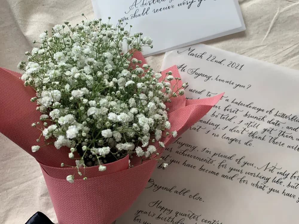 White baby's breath in pink paper lying on a handwritten letter