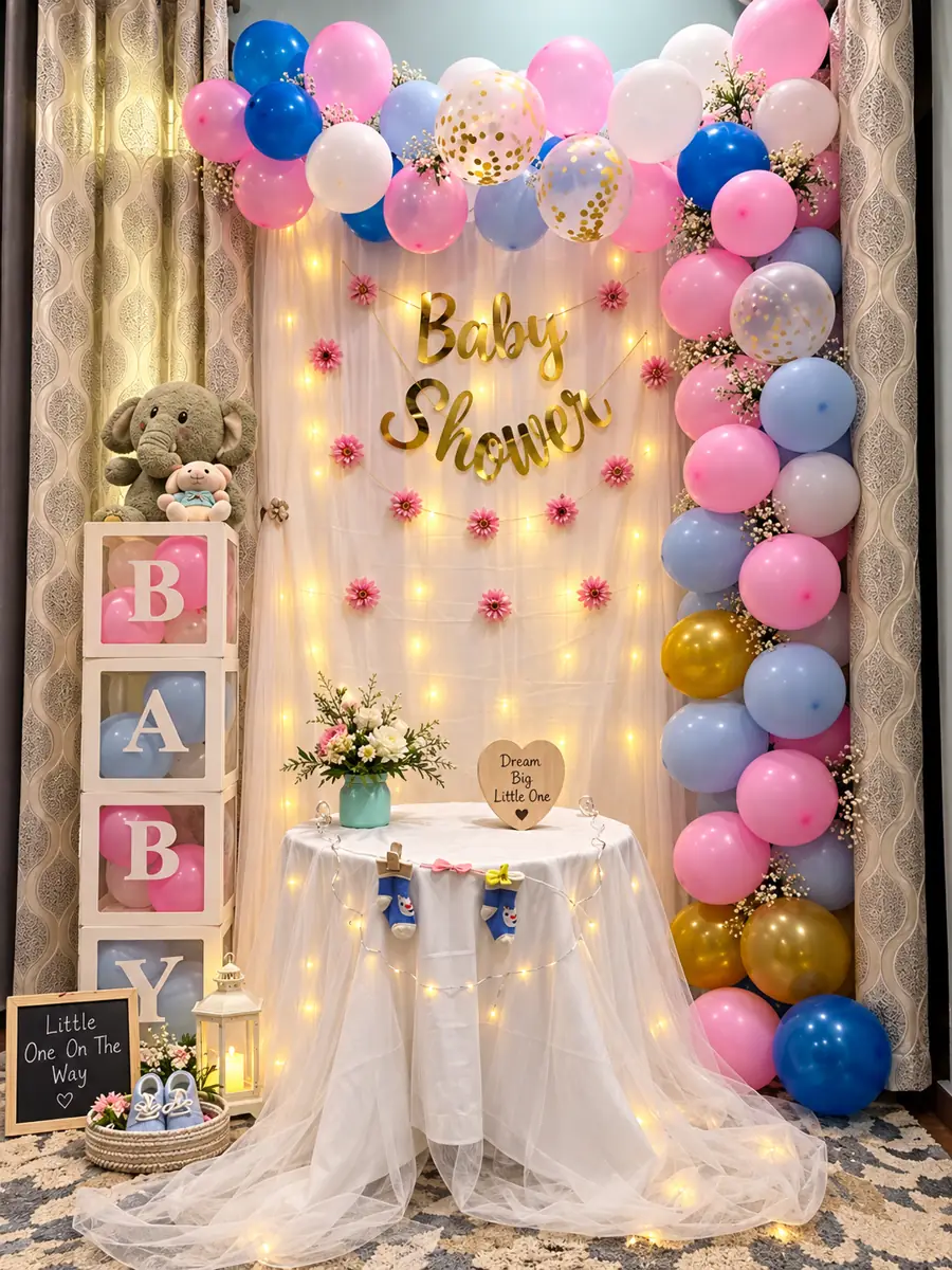 Baby Shower sign on a white curtain with fairy lights, a pink and blue balloon column and a small table