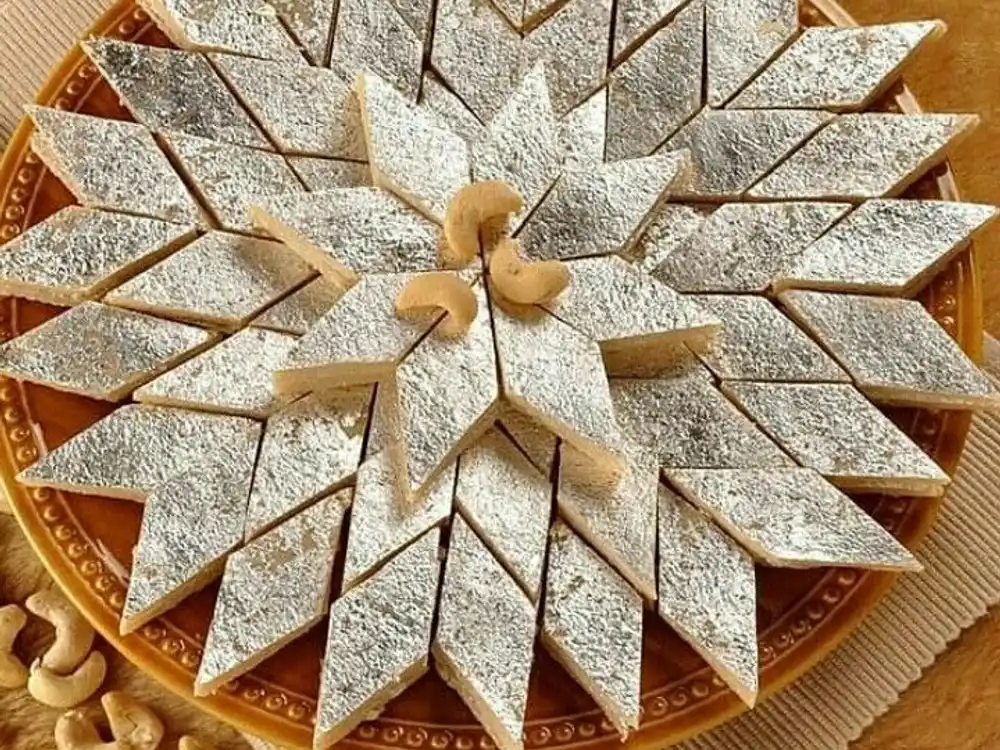 Kaju katli arranged in a star on a brass plate with cashews