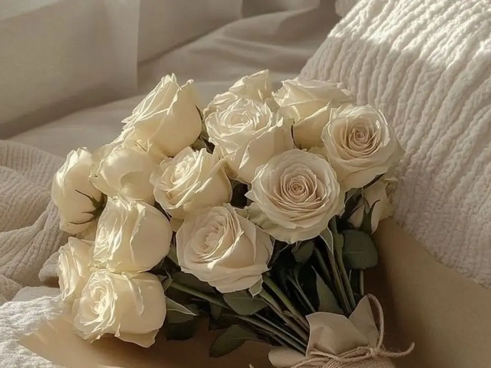 White roses tied with twine resting on cream linen