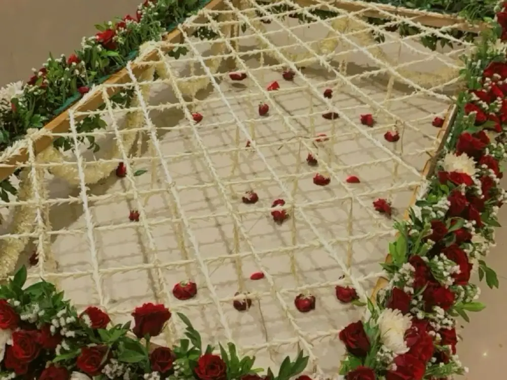Close view of a flower canopy with a white rope net, scattered red petals and red rose edging