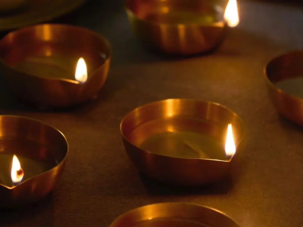 Lit brass diyas on a matte brown surface in warm light