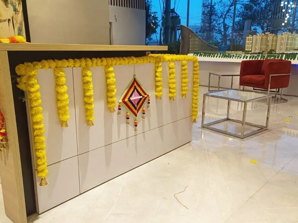 Reception counter with yellow and orange marigold strings hung along the front and a small woven ornament
