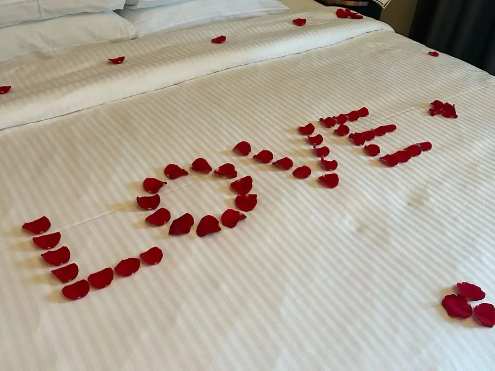 White hotel bedsheet with the word LOVE spelled in red rose petals