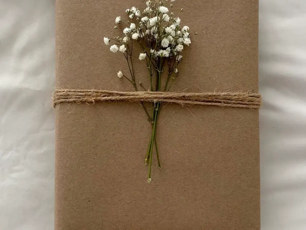 Brown paper gift wrapped with twine and a small bunch of white baby's breath