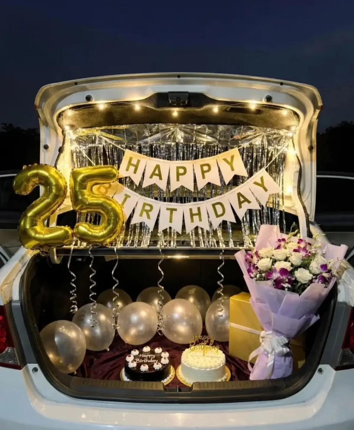 A car boot with clear balloons, a 25 foil, a bouquet and a Happy Birthday banner