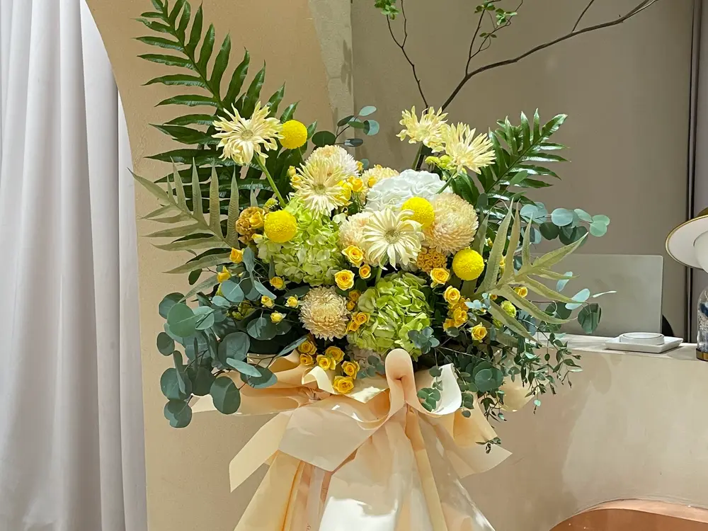 Yellow and cream chrysanthemum and hydrangea stand bouquet wrapped in peach paper