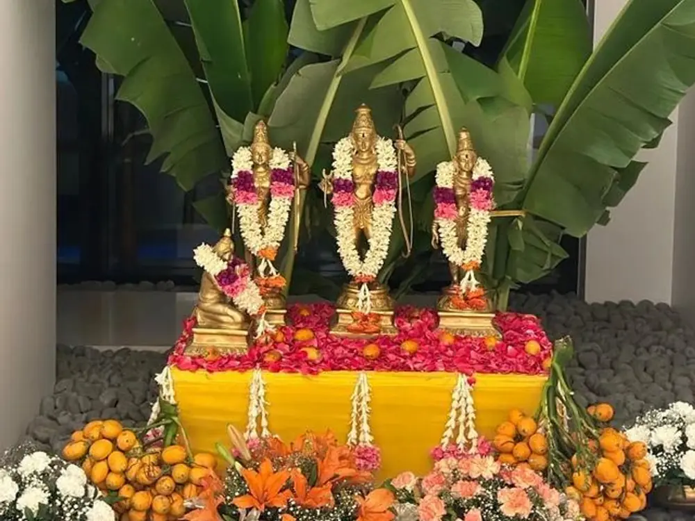 Ram, Sita and Lakshman idols on a yellow altar with rose petals and flower garlands