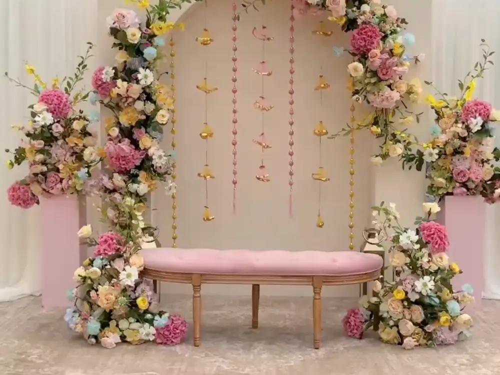 Pastel godh bharai backdrop with pink, yellow and blue flowers and a blush bench