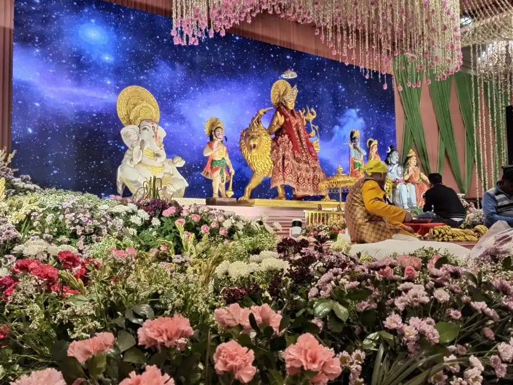 Mata ki chowki stage with deity idols above a field of pink carnations and white flowers