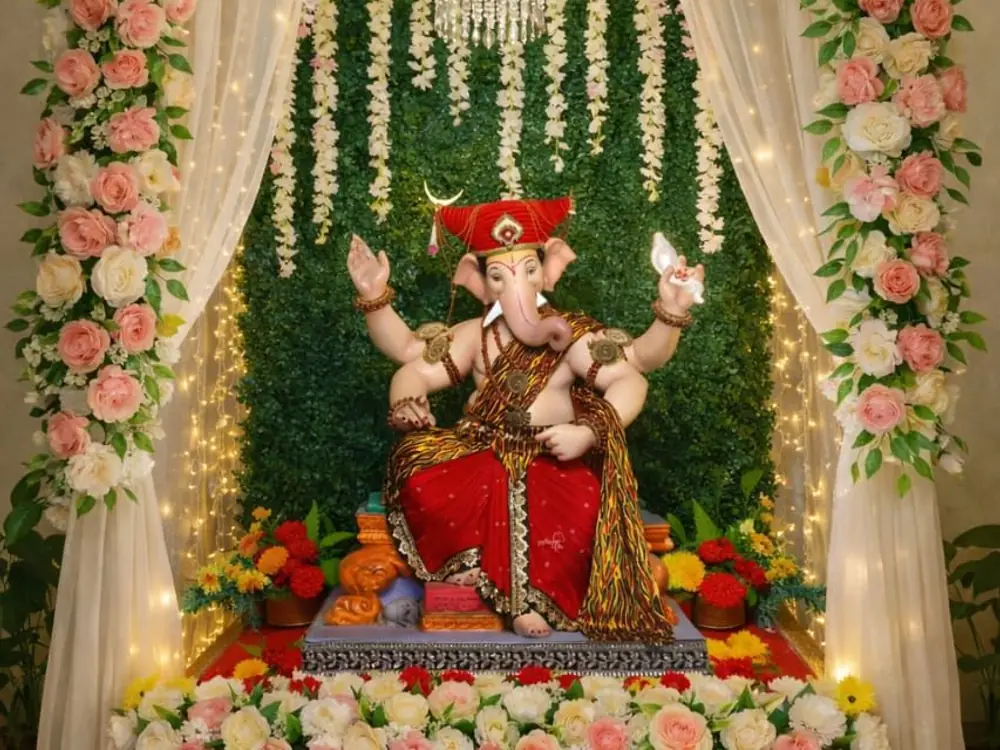 Ganesh idol framed by blush and white roses, sheer curtains and fairy lights