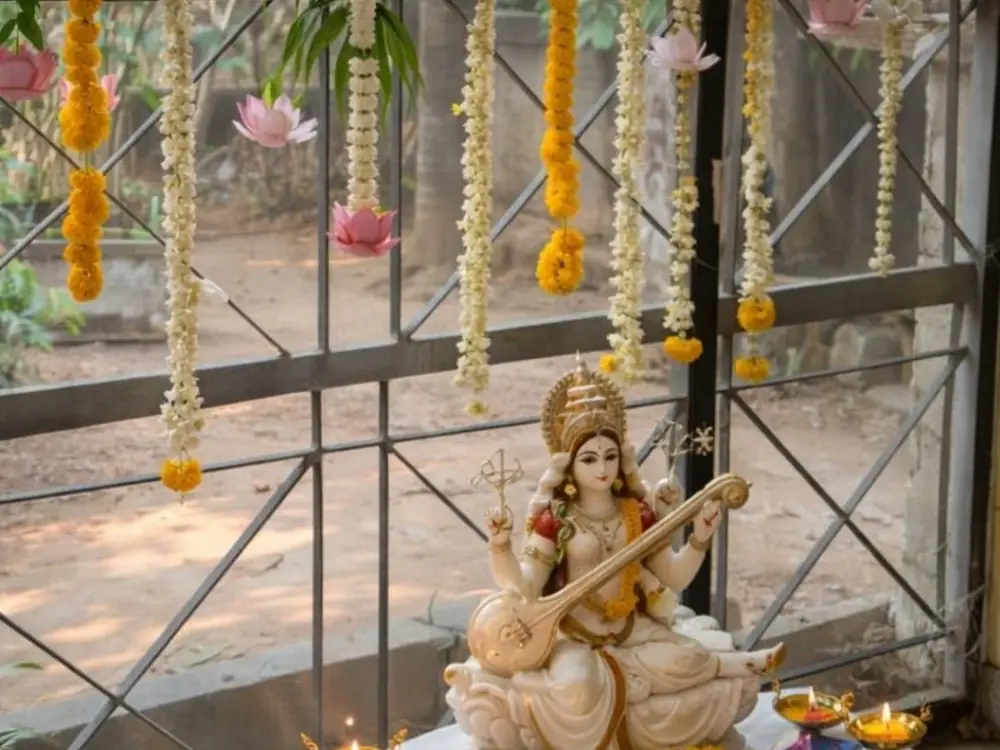 Saraswati idol with veena, white and yellow flower strings, books and brass lamps