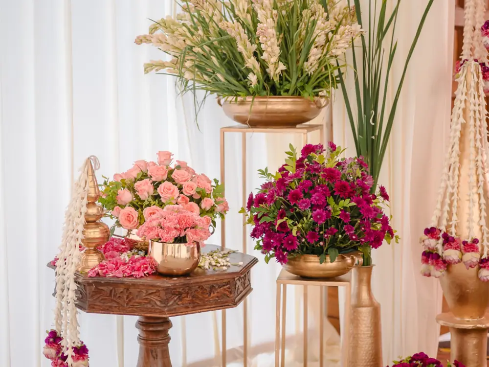 Pink roses, tuberoses and jasmine garlands arranged with brass pots for a milestone birthday