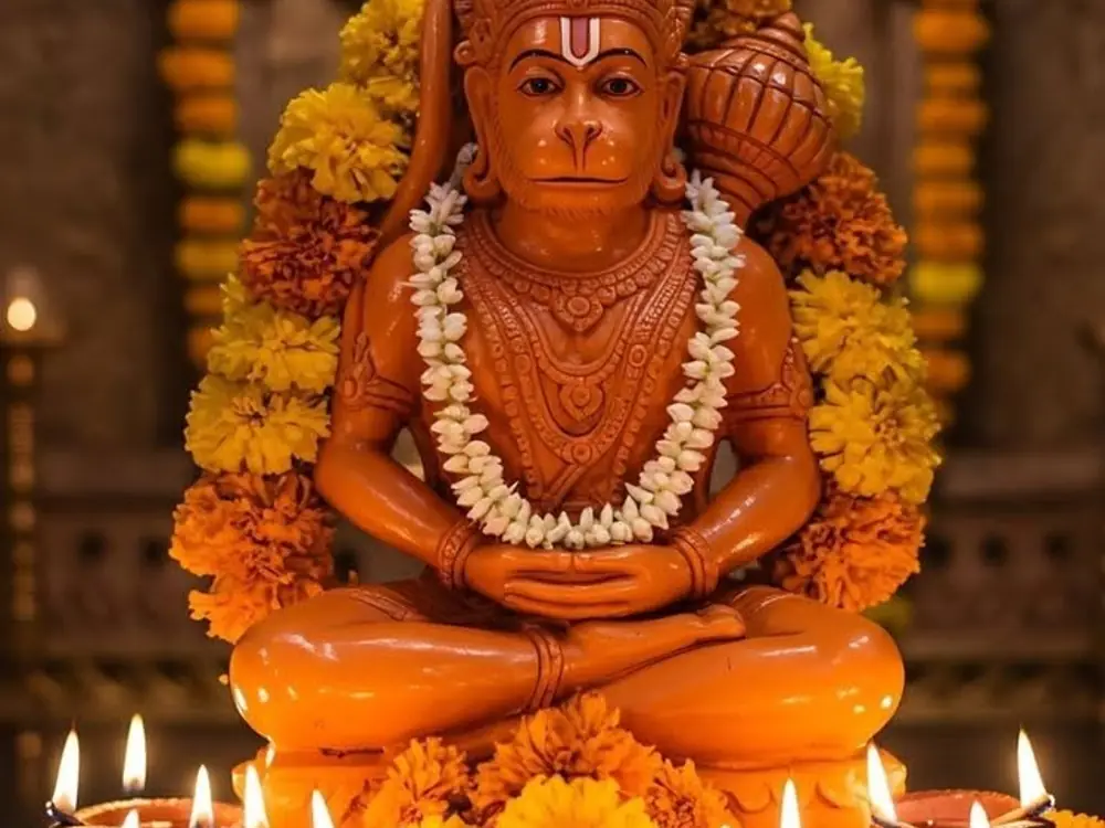 Hanuman idol with marigold and jasmine garlands and diyas lit below