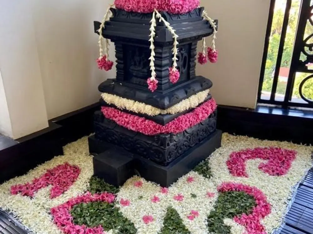 Tulsi vrindavan decorated with pink flowers and a white and pink petal rangoli