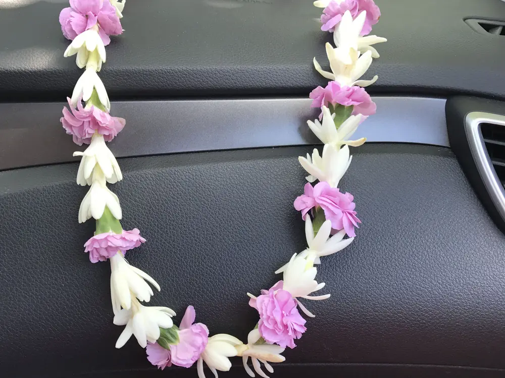 Pink and white flower garland laid across a car dashboard