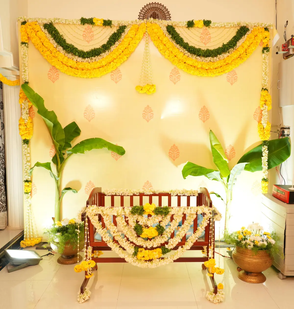 A wooden cradle wrapped in marigold and white flowers for a naming ceremony