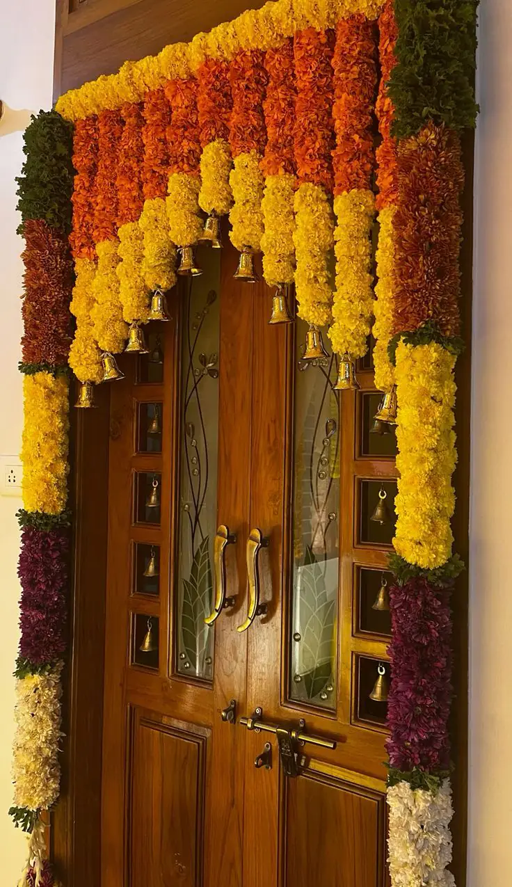 Marigold and flower garlands framing a wooden double door with brass handles