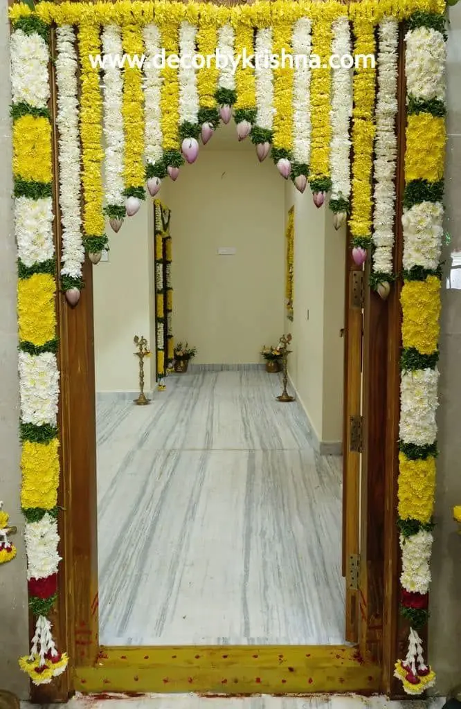 Entrance arch of white and yellow flower garlands over a long corridor
