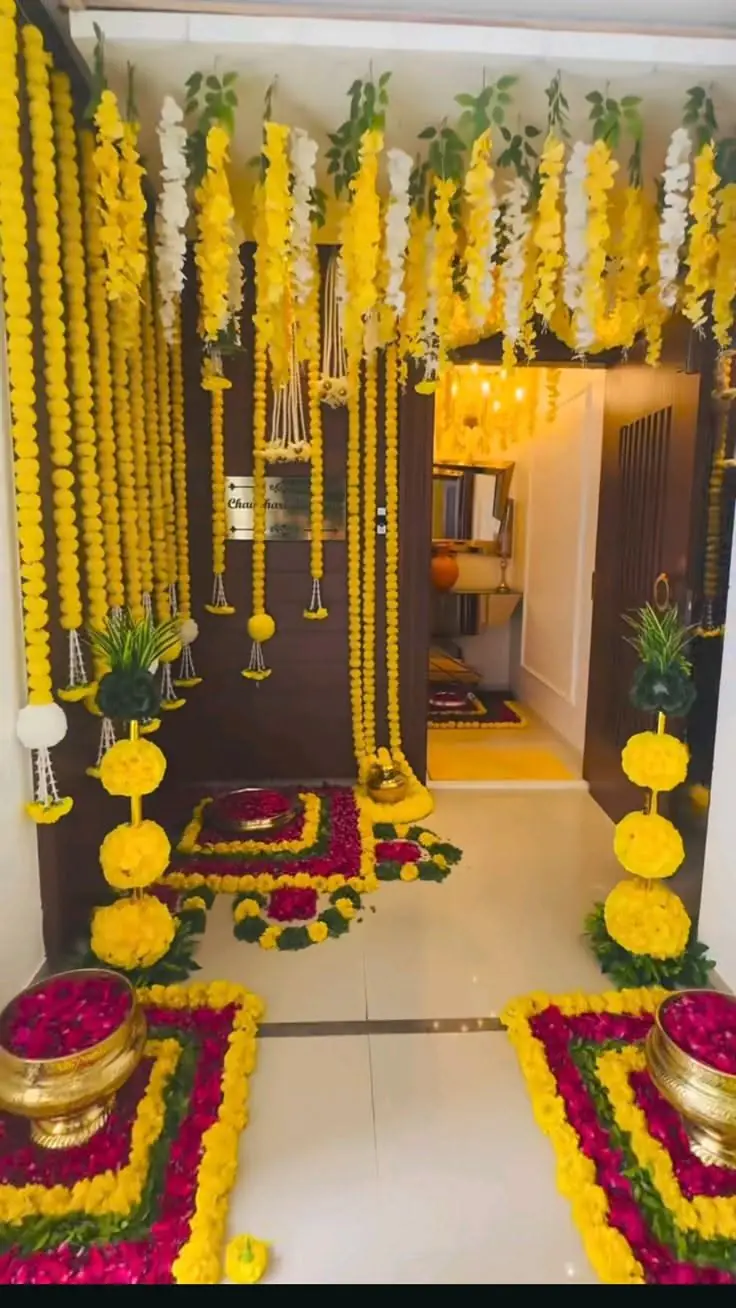 Door with hanging marigold strings, potted plants and a flower rangoli