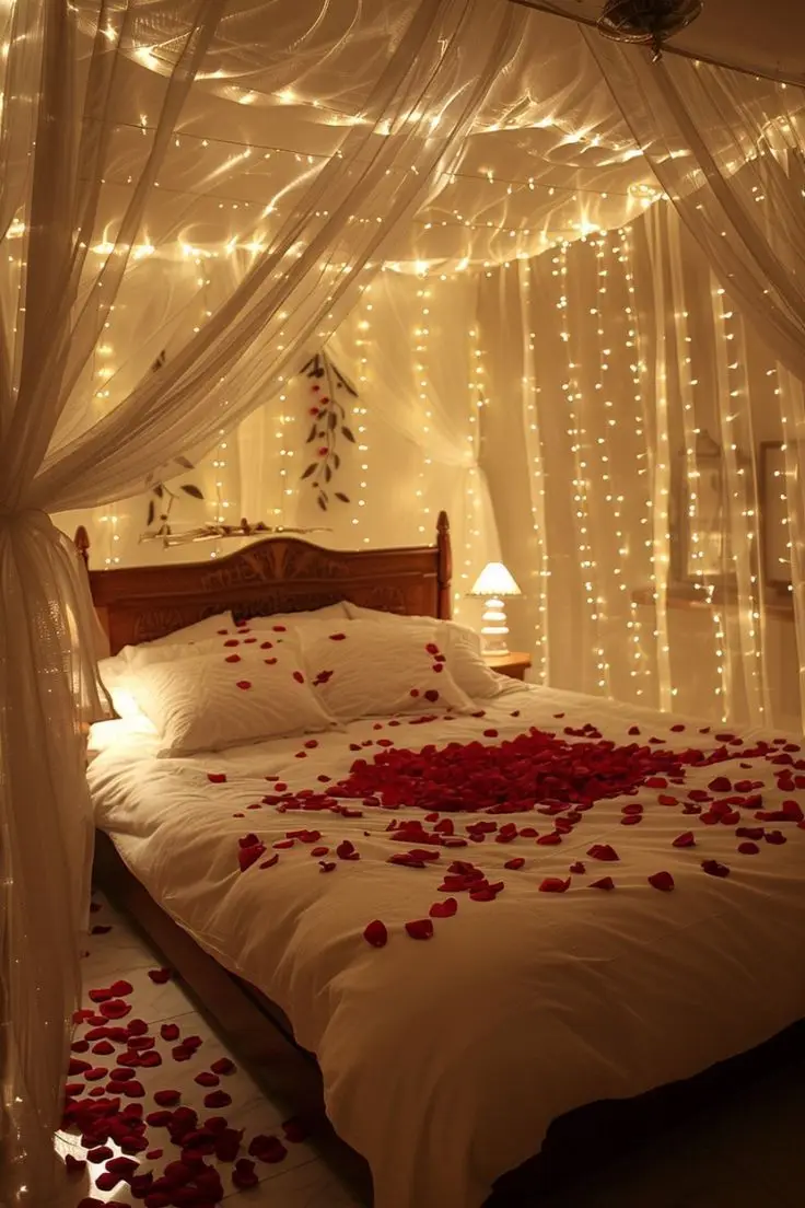 A canopy bed with fairy lights and a rose petal heart on the bed