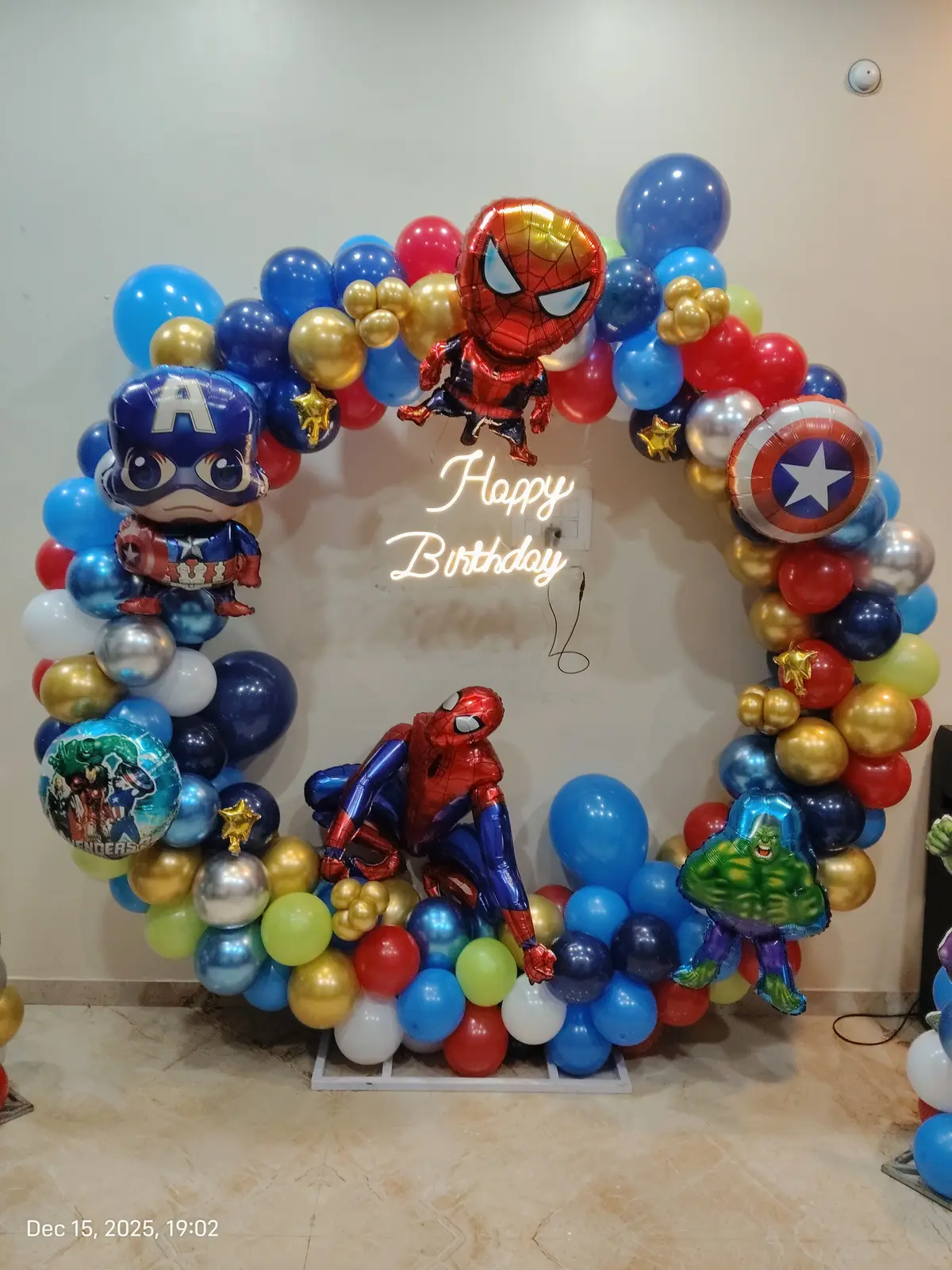 A superhero theme birthday ring of red, blue and yellow balloons with hero foils