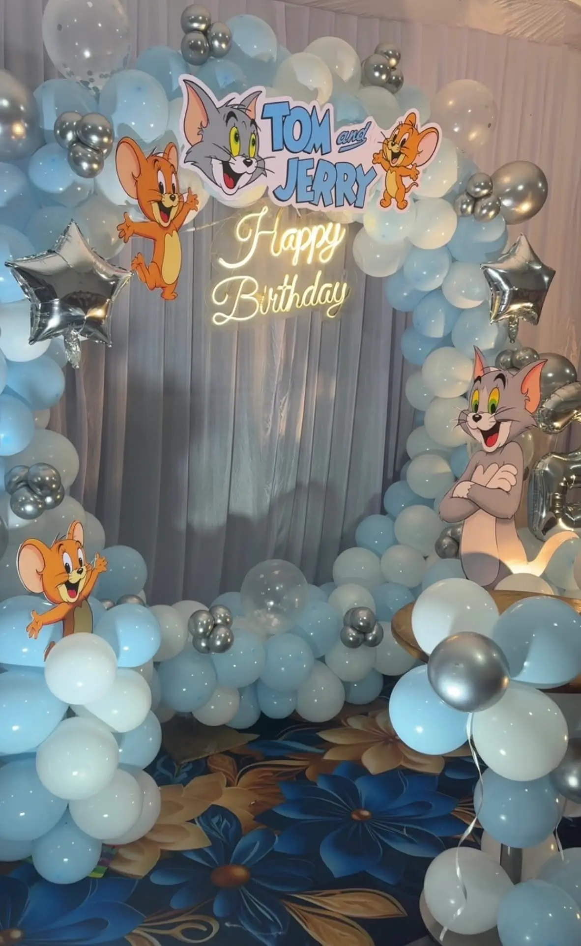 A cartoon theme birthday ring of blue and white balloons with cat and mouse foils