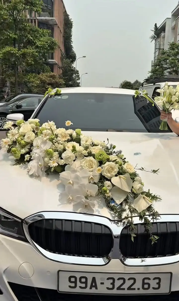 White car with a long white and green flower spray across the bonnet