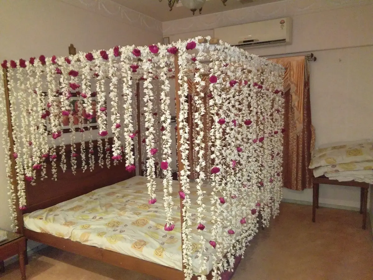 Bed canopy of hanging jasmine strings with a red and pink flower bed