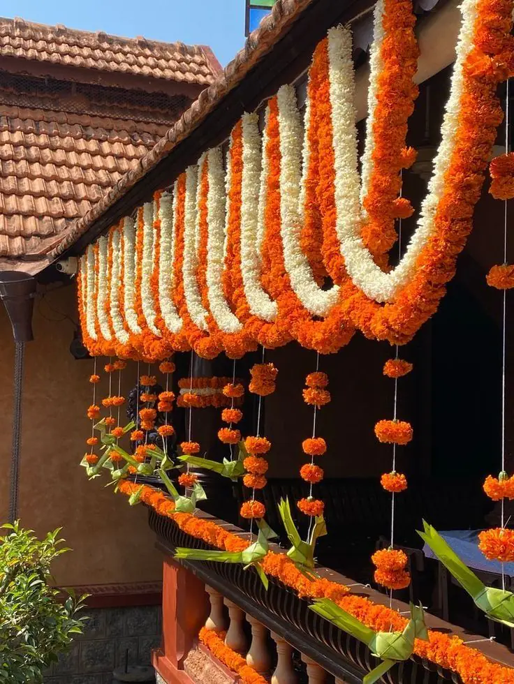 Tiled house front with marigold and white flower garlands hung in rows