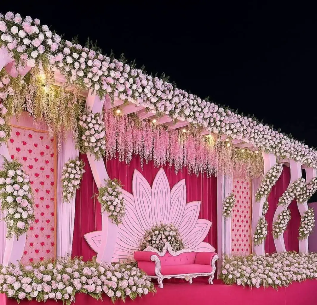 Pink wedding stage with a lotus-shaped backdrop and white flower borders
