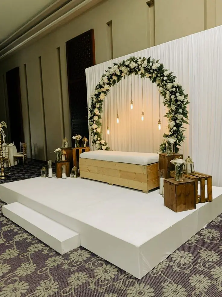Floral ring backdrop with hanging bulbs and a white platform sofa
